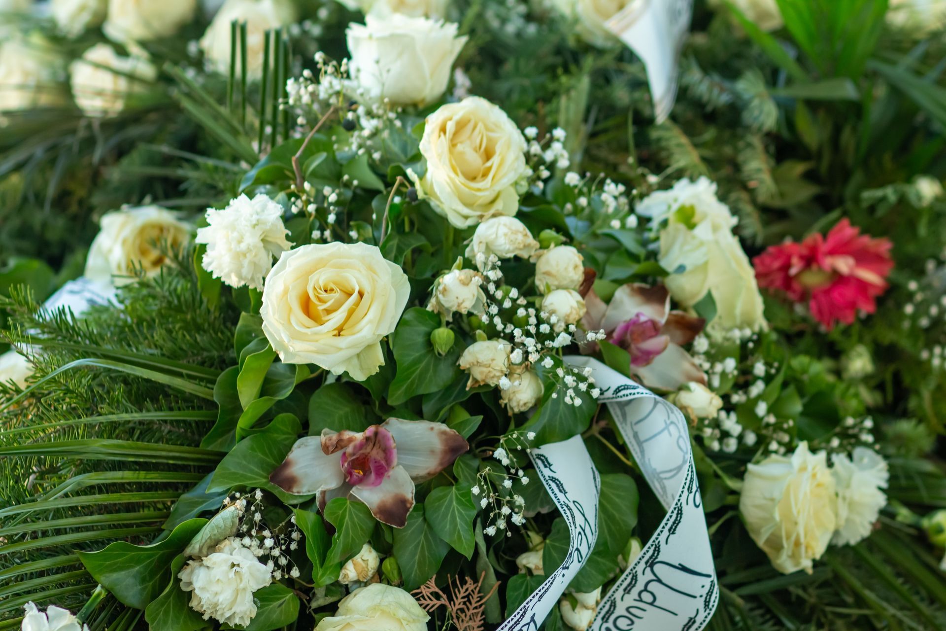 White and pale yellow roses with greenery and baby's breath in a floral arrangement