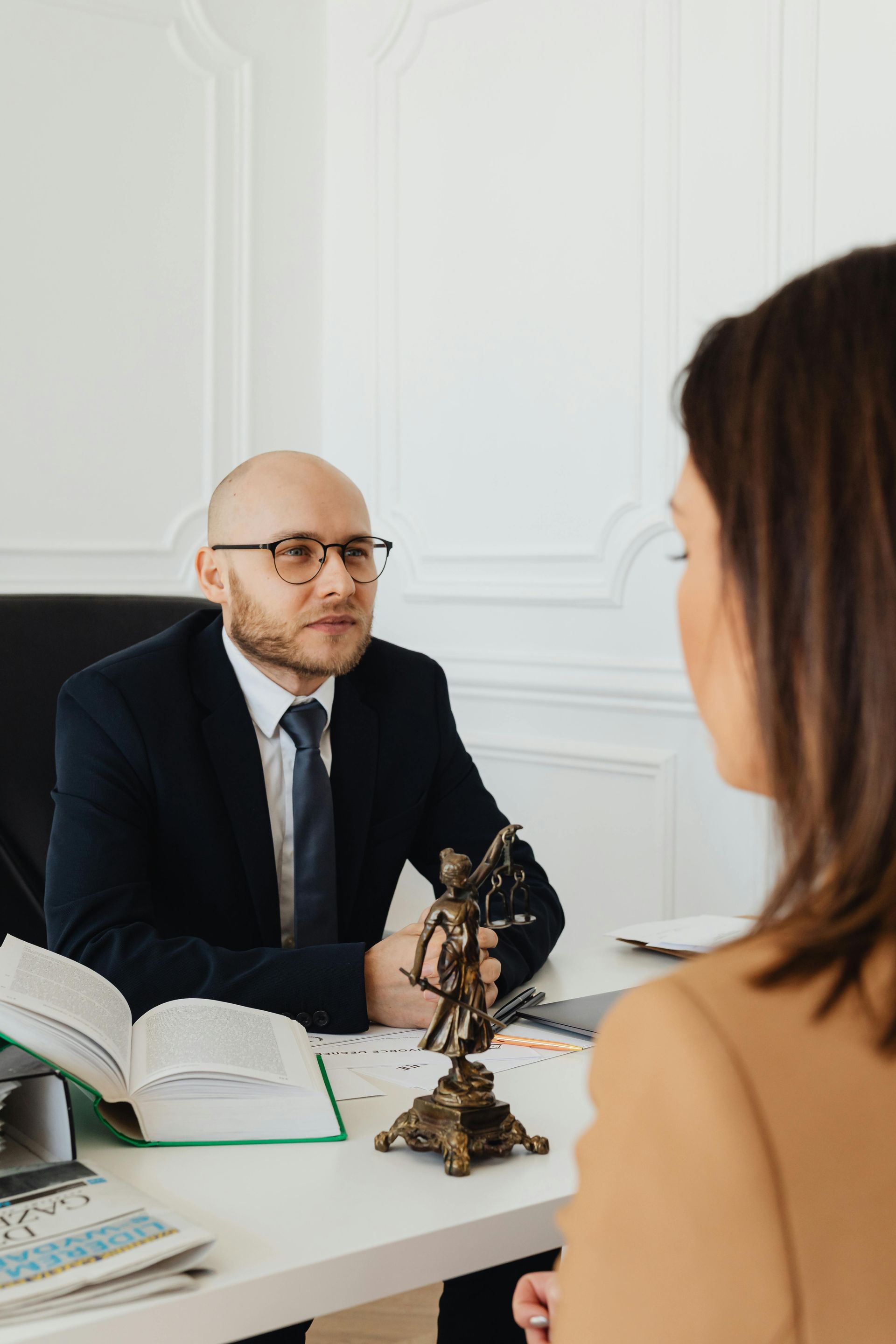Public adjuster in suit consulting with client across desk during insurance claim discussion