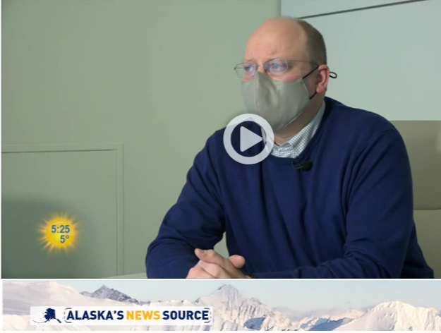 Man in a blue sweater and mask, indoors, seated and speaking. Alaska's News Source logo at the bottom.