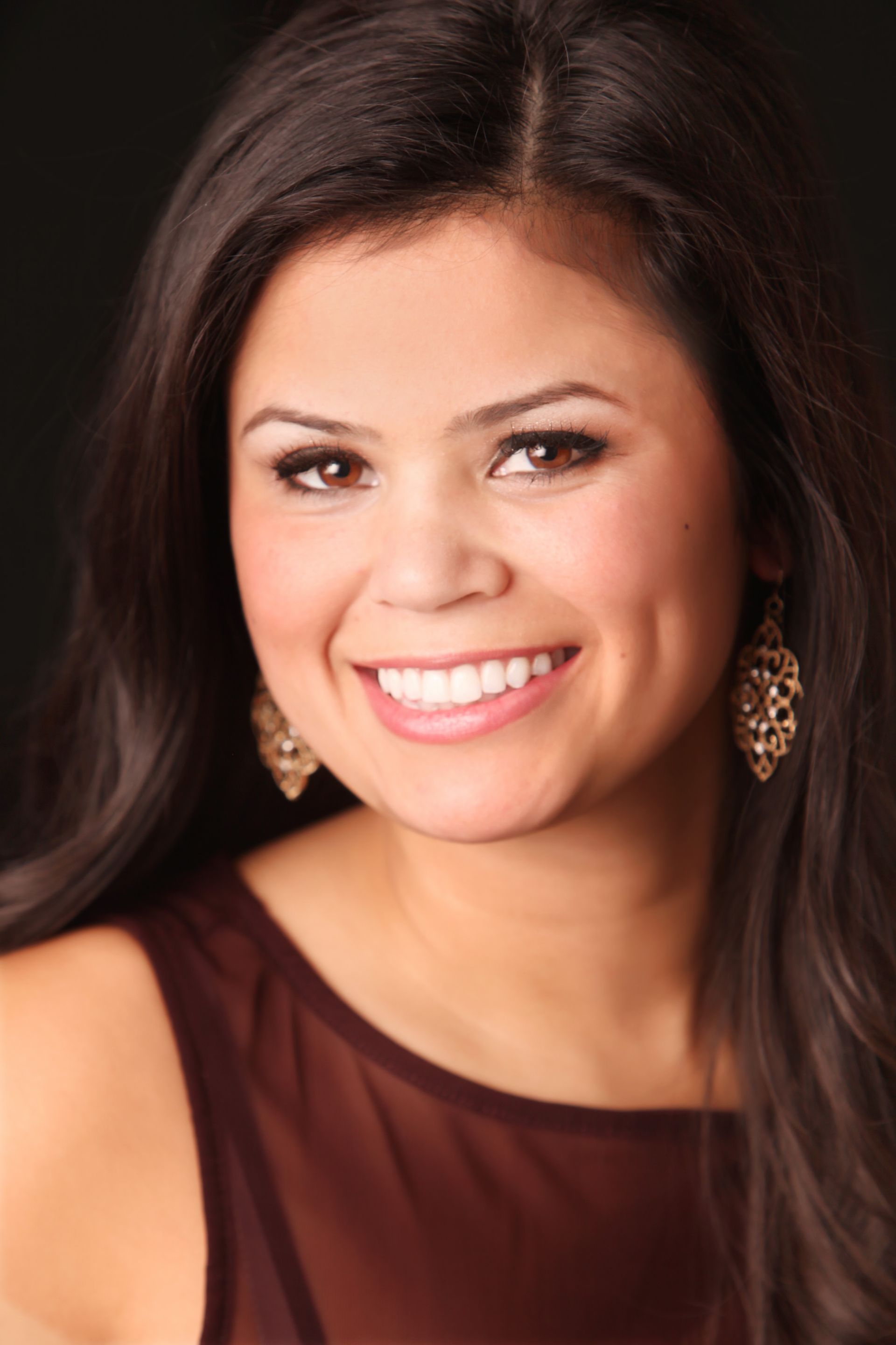 Woman with brown hair wearing a brown top.
