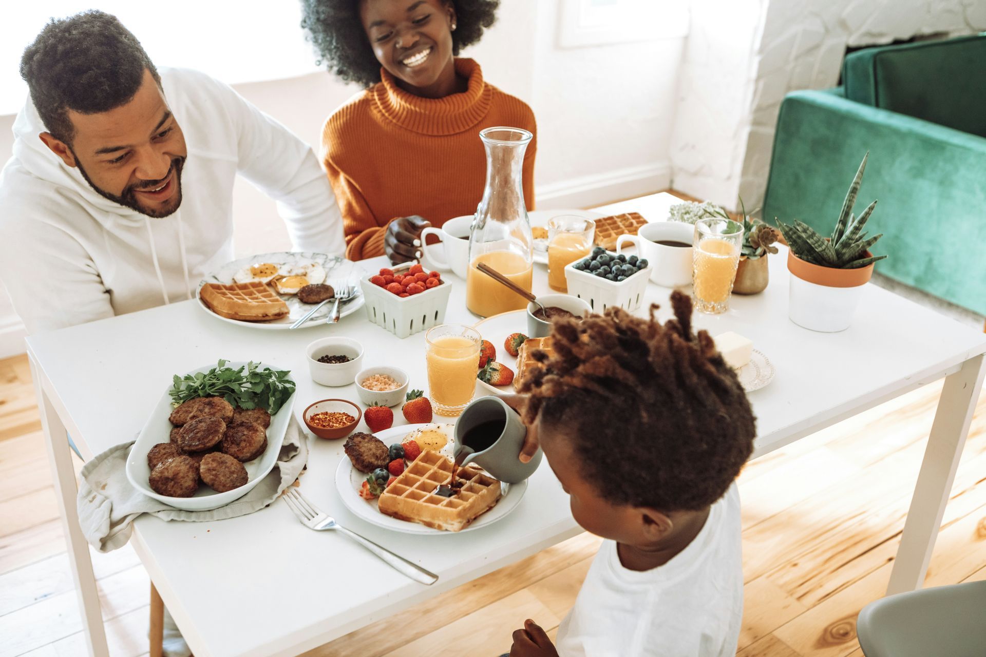 Family at breakfast table with waffles, fruit, and smiles.