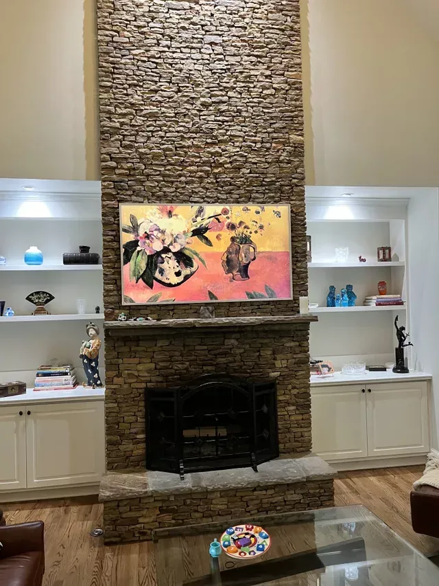 A living room with a fireplace and a painting on the wall above it.