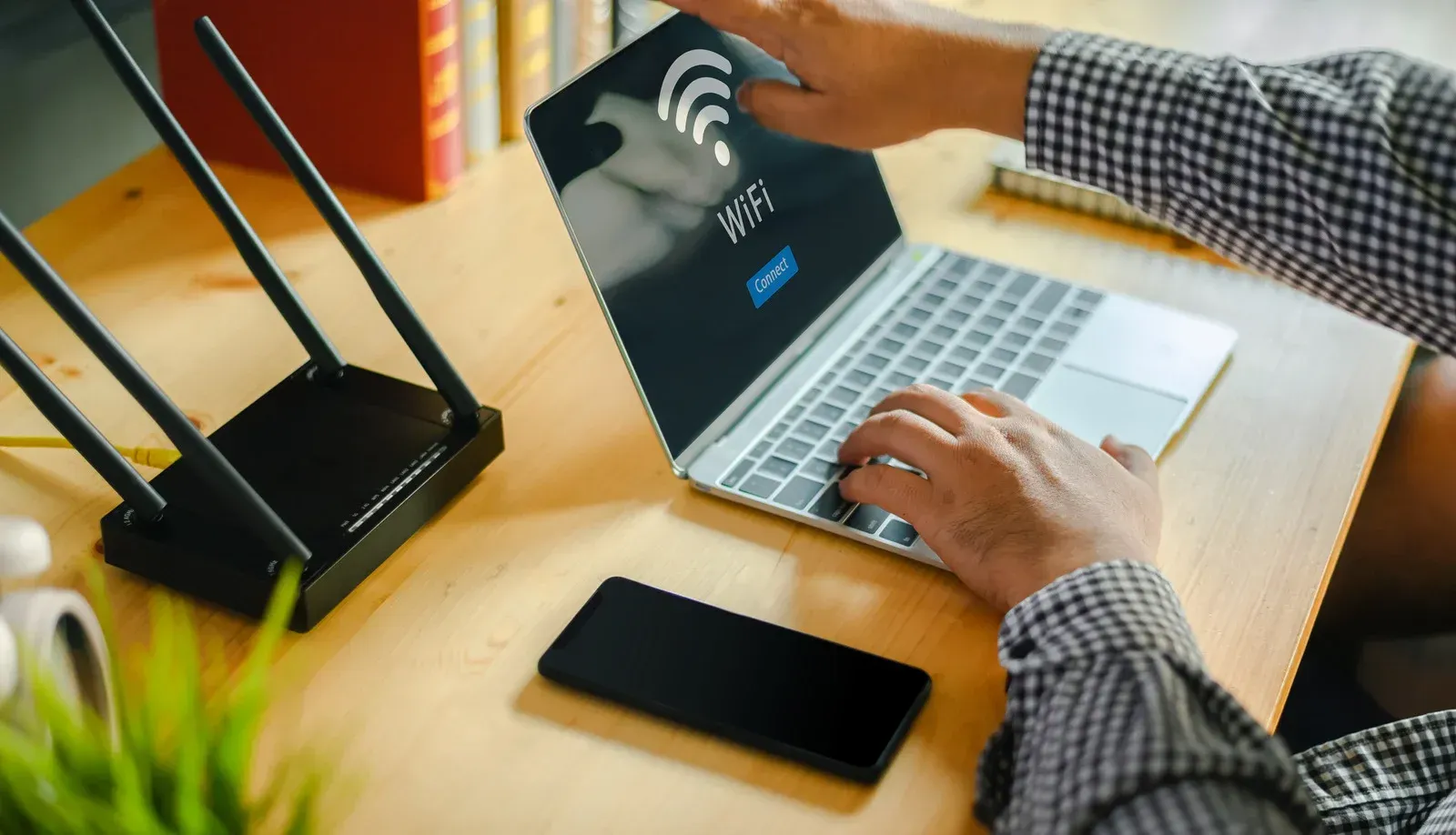 A person is using a laptop computer on a wooden desk.