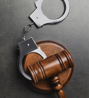 A pair of handcuffs sitting on top of a wooden judge 's gavel.