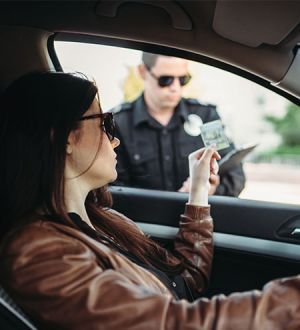 A woman is sitting in a car talking to a police officer