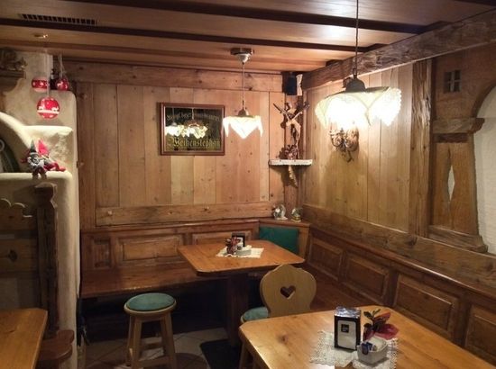 Accogliente divanetto in legno in stile ristorante con tavoli, panche, sgabelli e calde applique a parete.