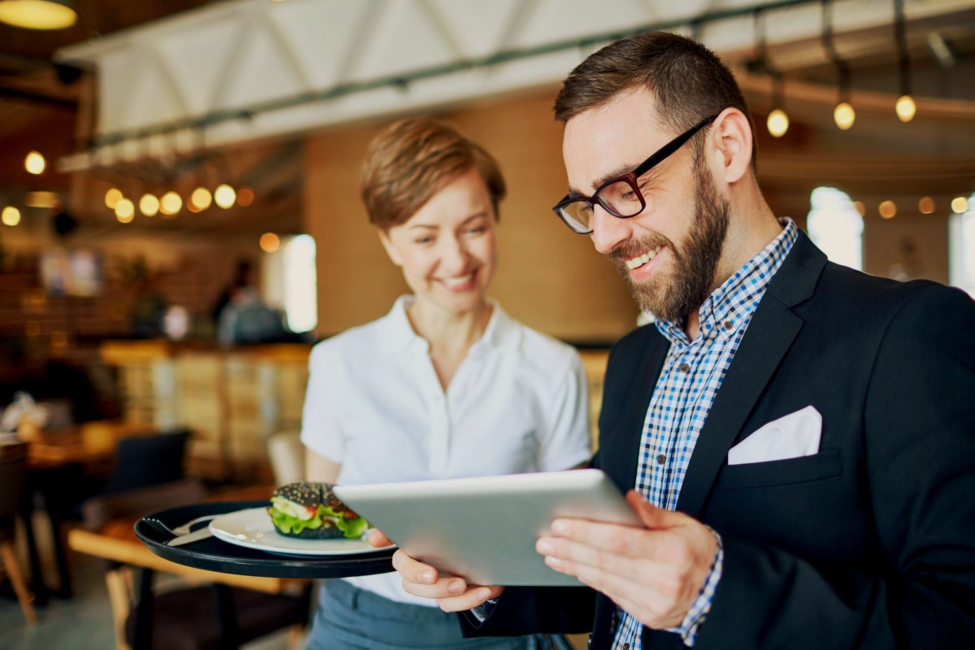 The restaurant owner and one of his employee is checking the restaurant operations report on a tablet.