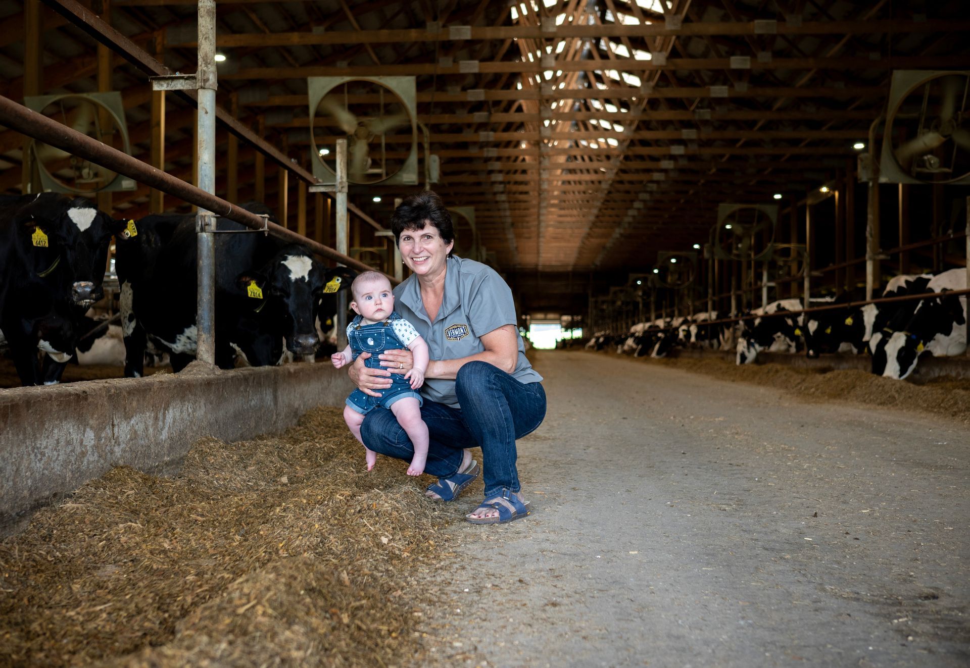 Vermont Cattlemen Partner Elaine Brisson holding her grandchild in the dairy farm feed ally