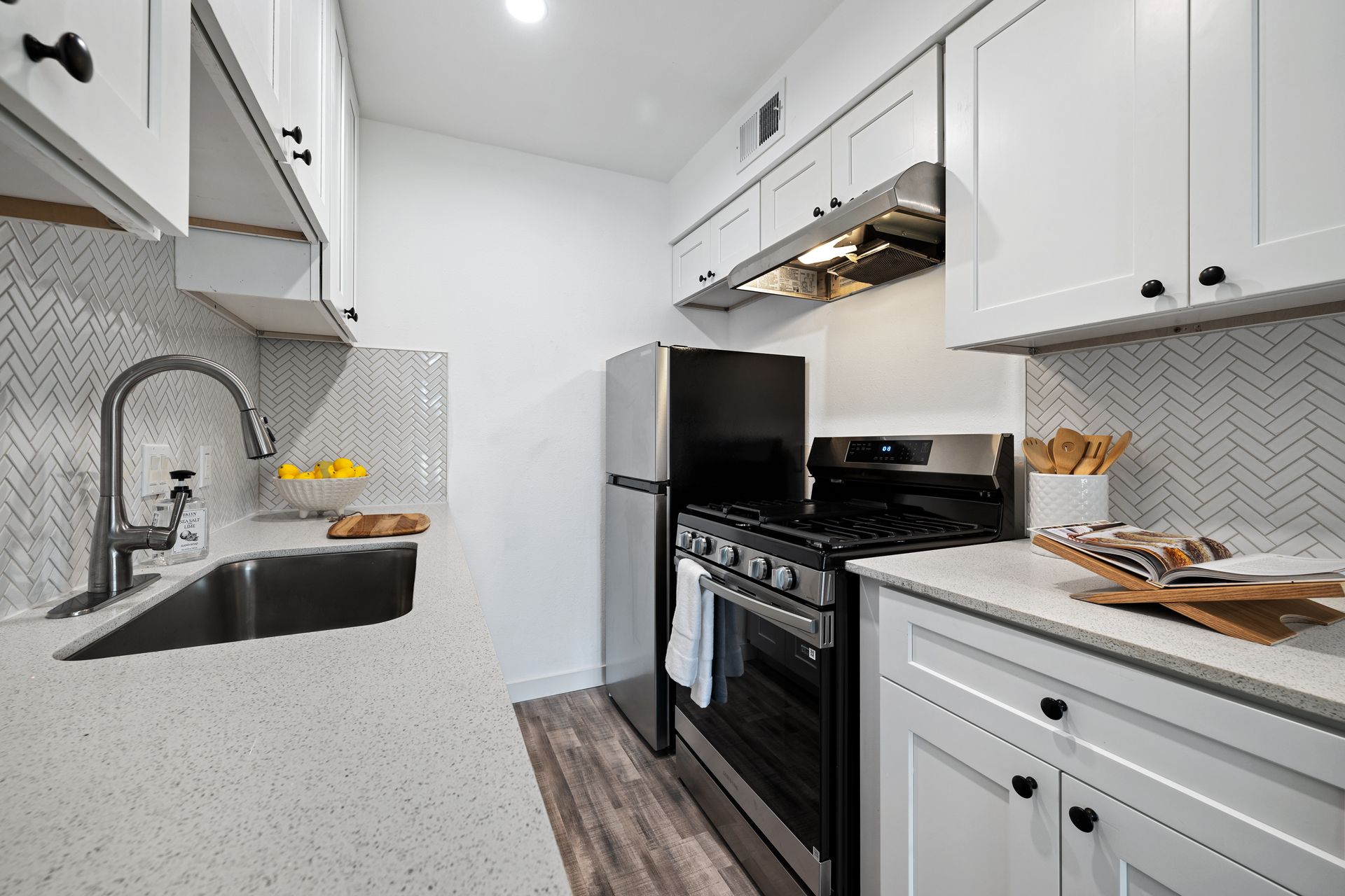 Bright modern galley kitchen with white cabinets, black stove, and white quartz counters