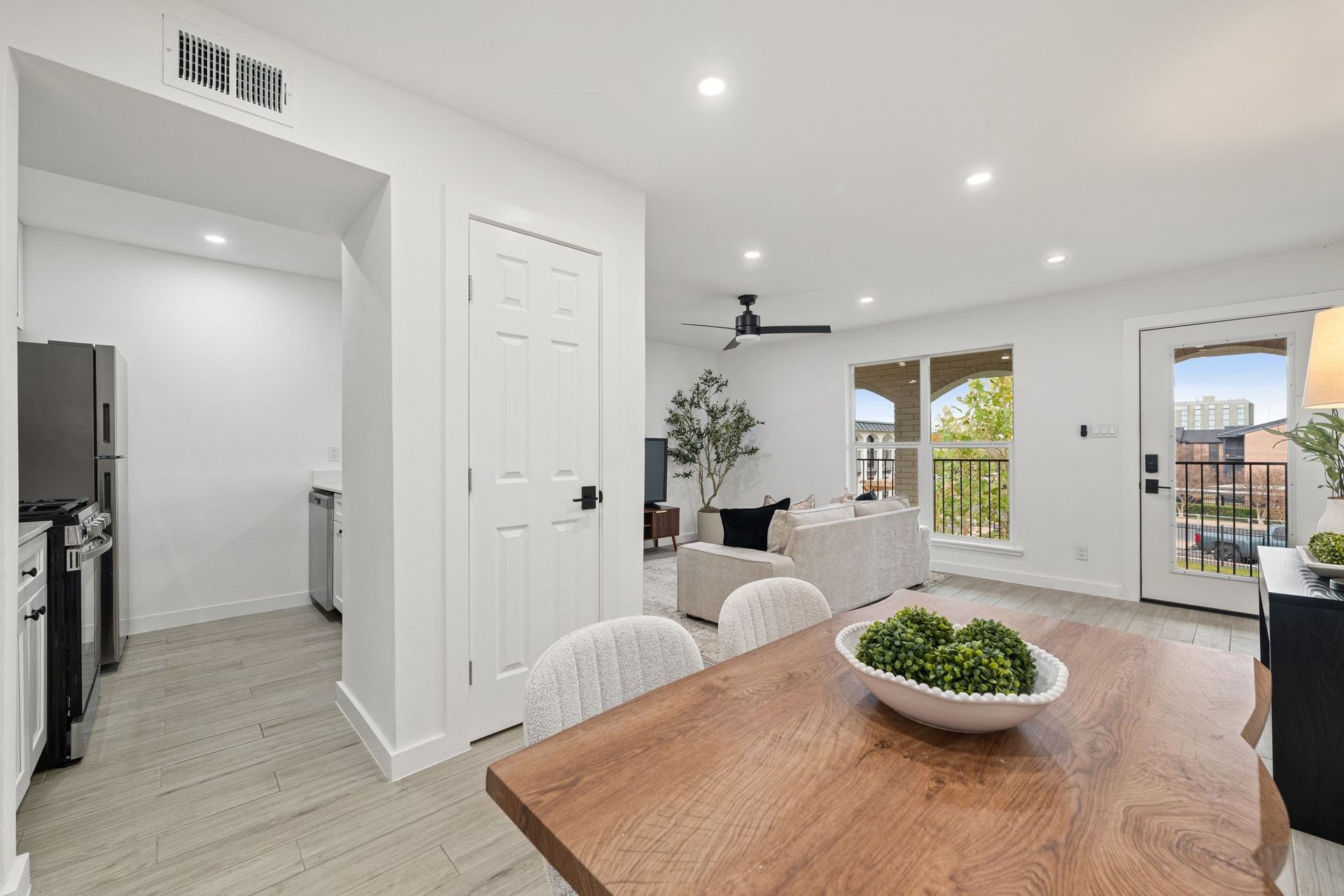 Bright modern dining area with wood table, kitchen alcove, and sliding doors to a patio