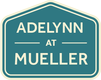 Teal neighborhood sign reading &ldquo;ADEL YNN AT MUELLER&rdquo; with cream border and text