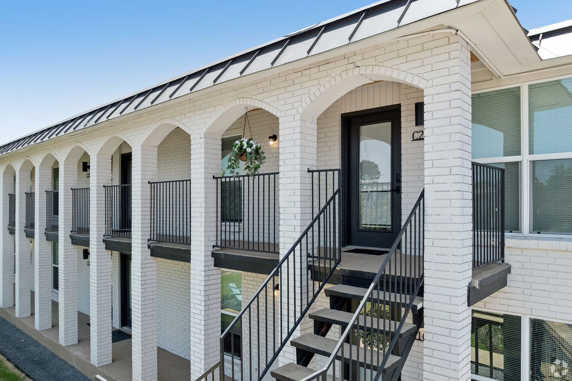 White apartment building exterior with arched balconies and black metal staircases
