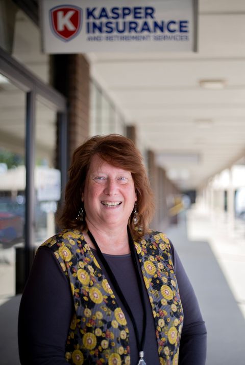 Woman smiling outside a Kasper Insurance storefront in a covered walkway