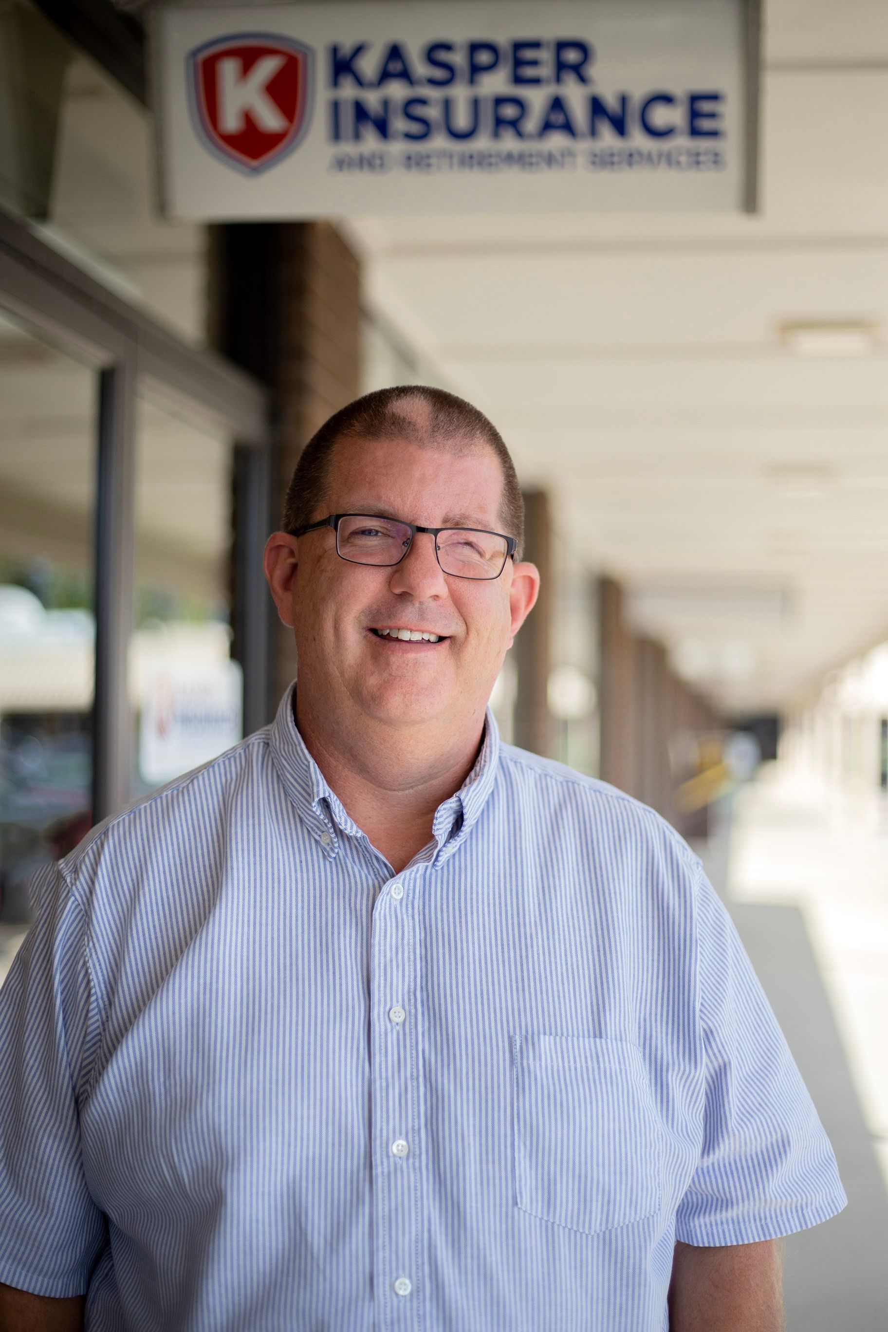 Smiling man in striped shirt standing outside Kasper Insurance office