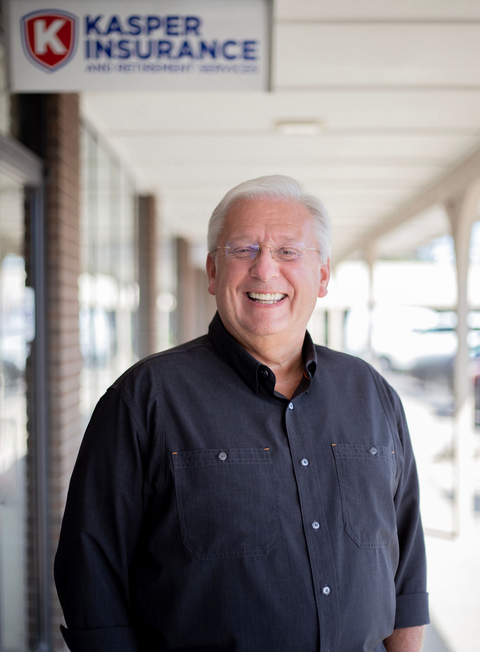 Smiling man in a black shirt standing outside a Kasper Insurance office