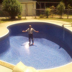A man is standing in the middle of a large swimming pool.