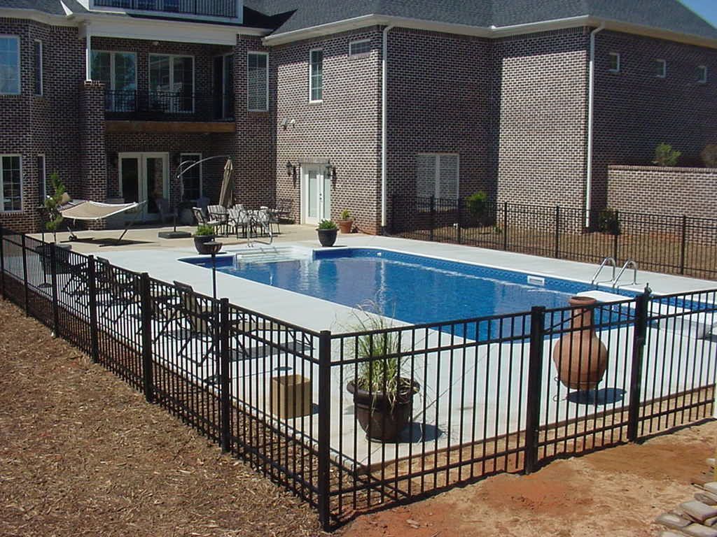 A large swimming pool is surrounded by a metal fence