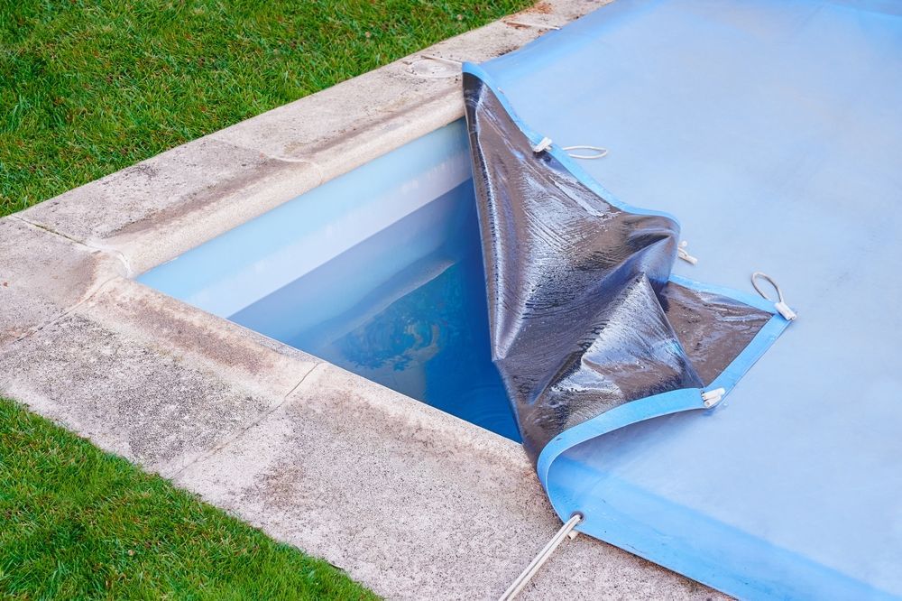 A swimming pool is covered with a blue tarp.