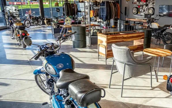 Blue motorcycle parked outside a café with tables and chairs on a sunny patio