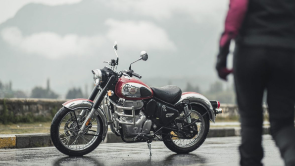 Red and black motorcycle parked on a wet road, with a blurred person standing in the foreground.