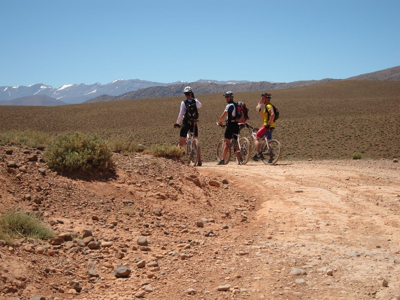 Mountainbikers genieten van het uitzicht op de besneeuwde toppen van de Hoge Atlas.