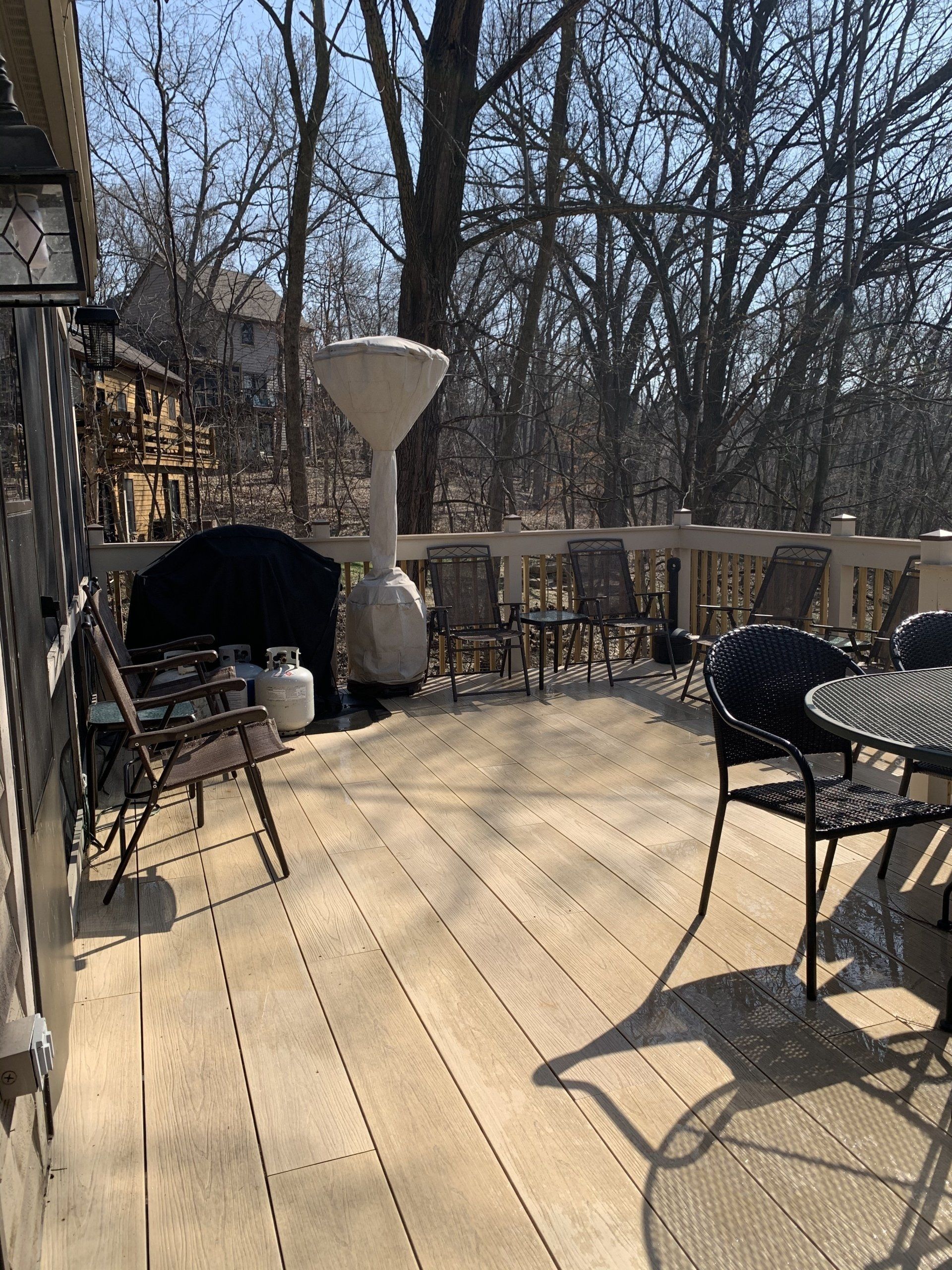 Wooden deck with outdoor furniture, trees in the background, and a patio heater.