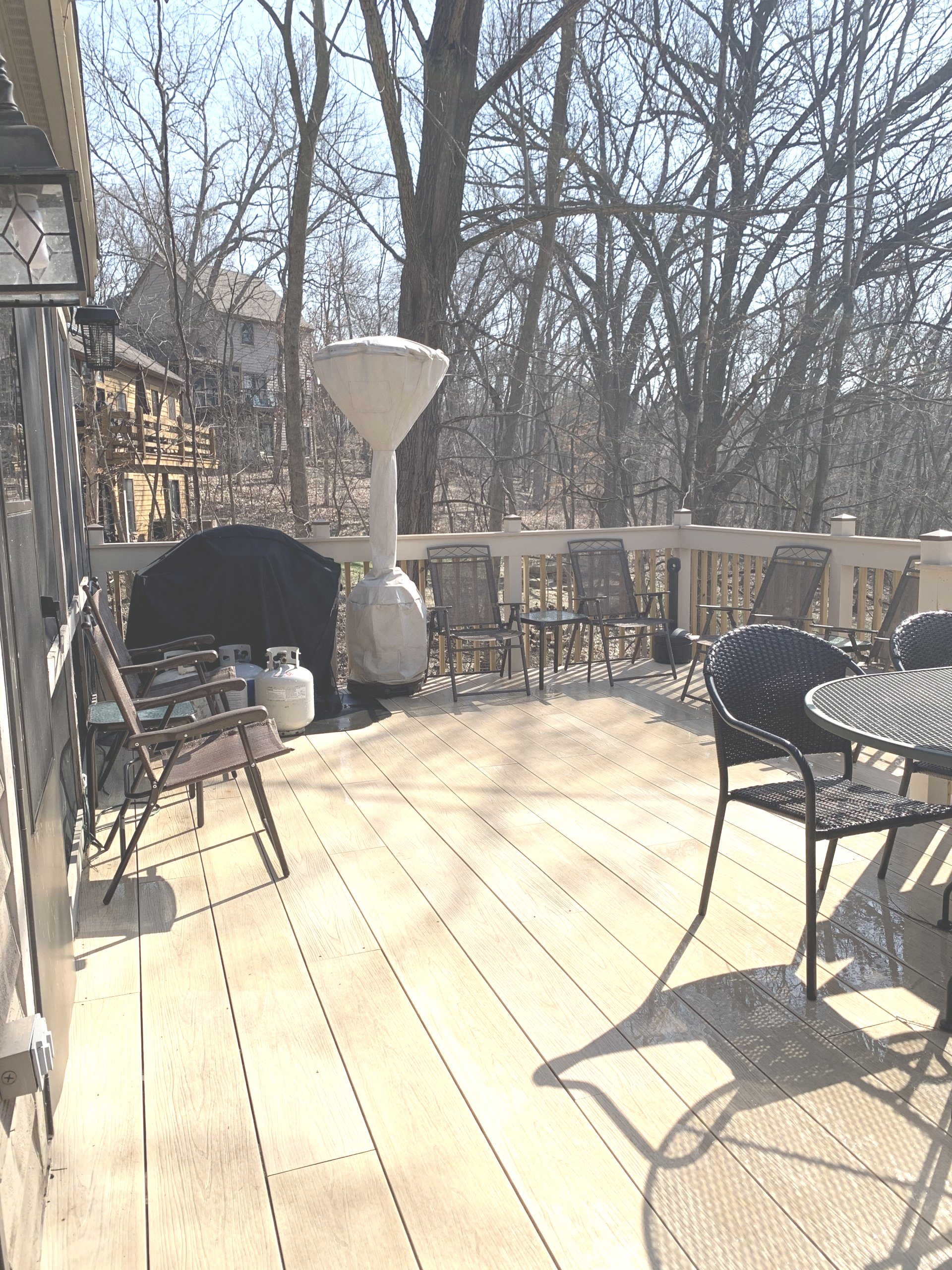 Outdoor deck with grill, seating, and a tall, decorative element; trees in the background.