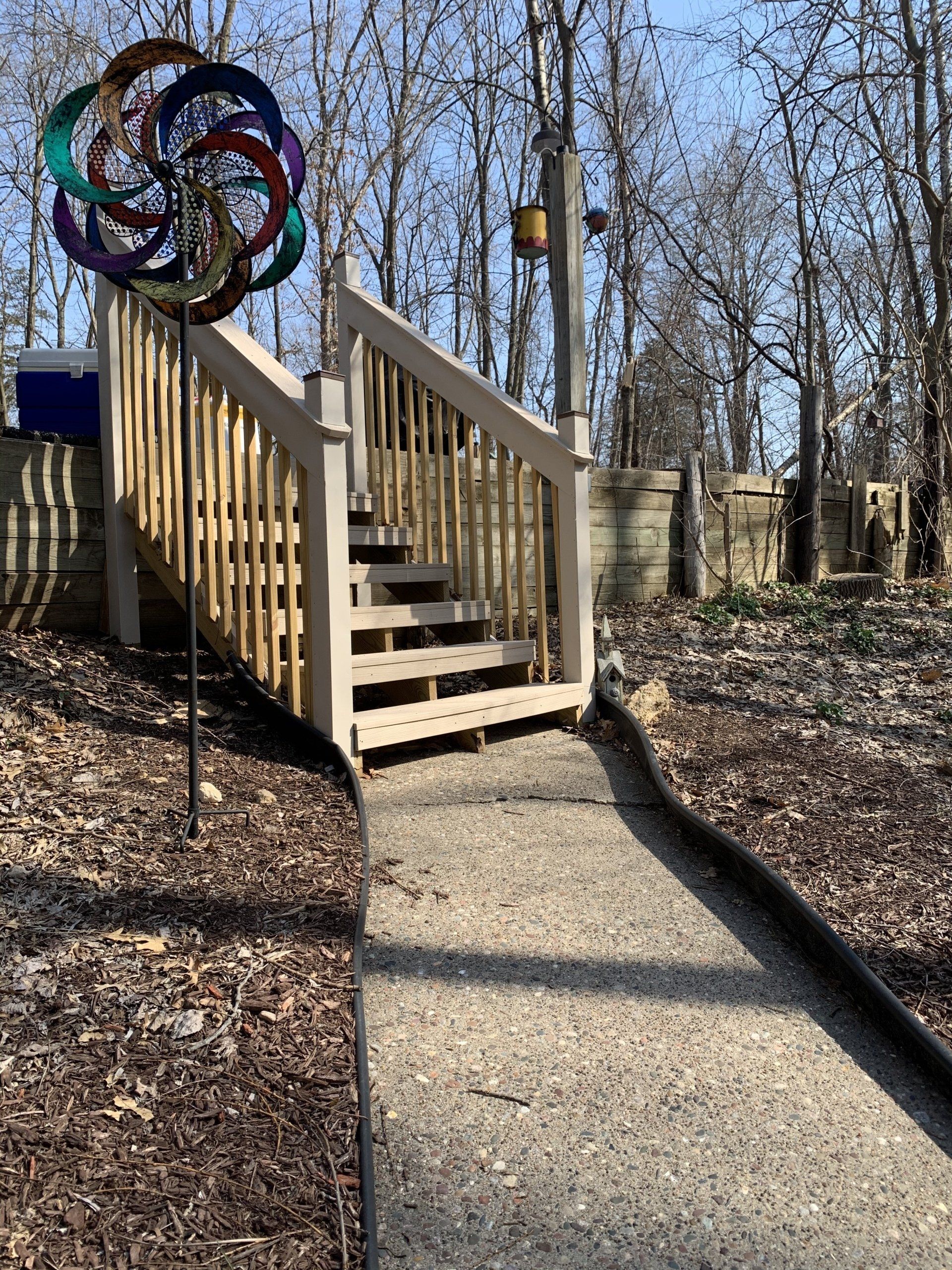 Pathway with stairs leading to a wooden deck, topped by a colorful pinwheel.