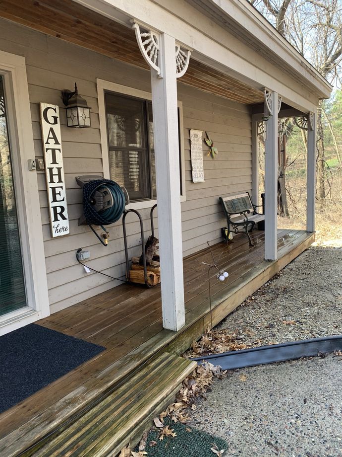A porch with a wooden deck, a hose, and a 