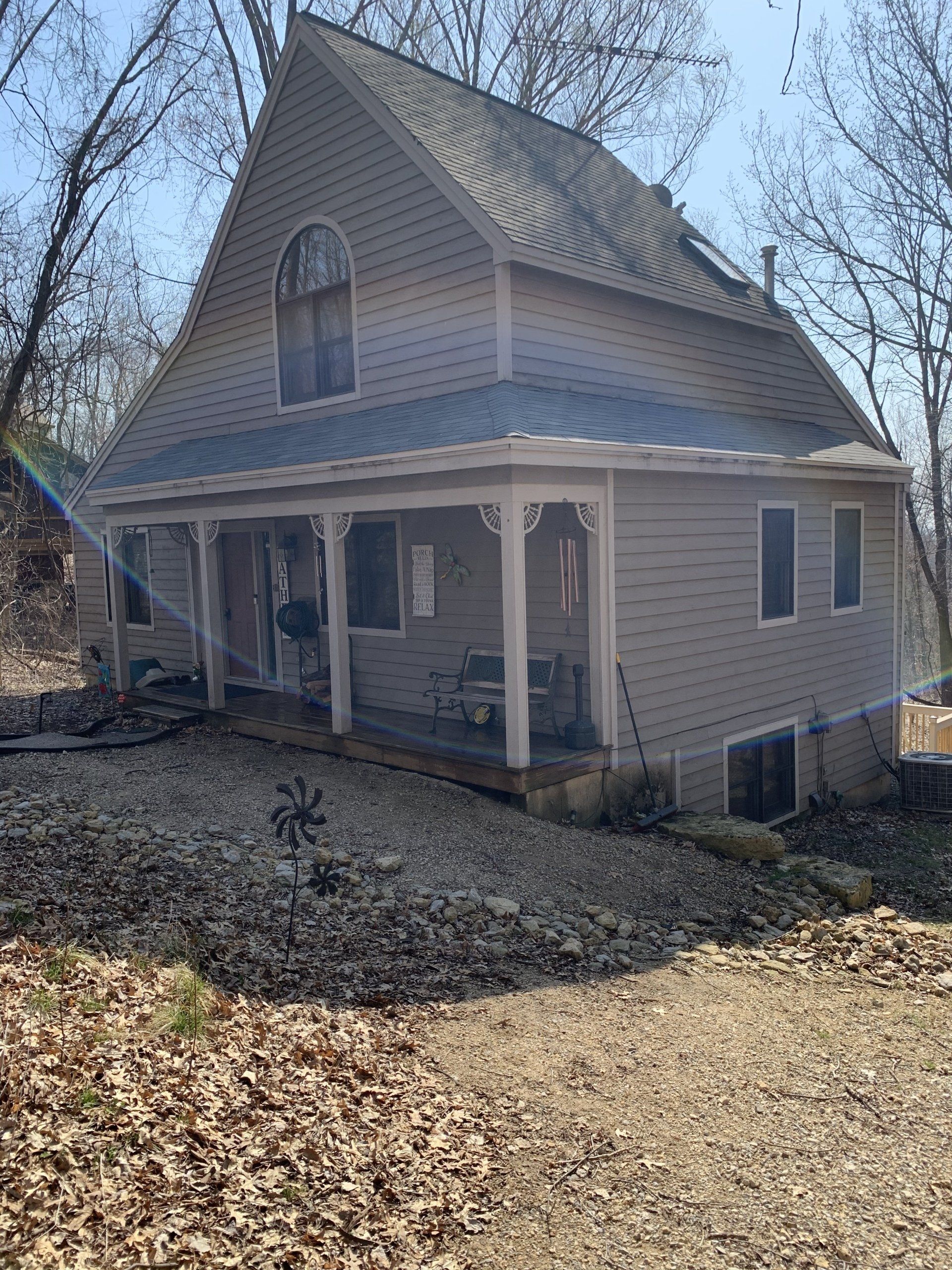 Tan house with porch and gravel landscaping.