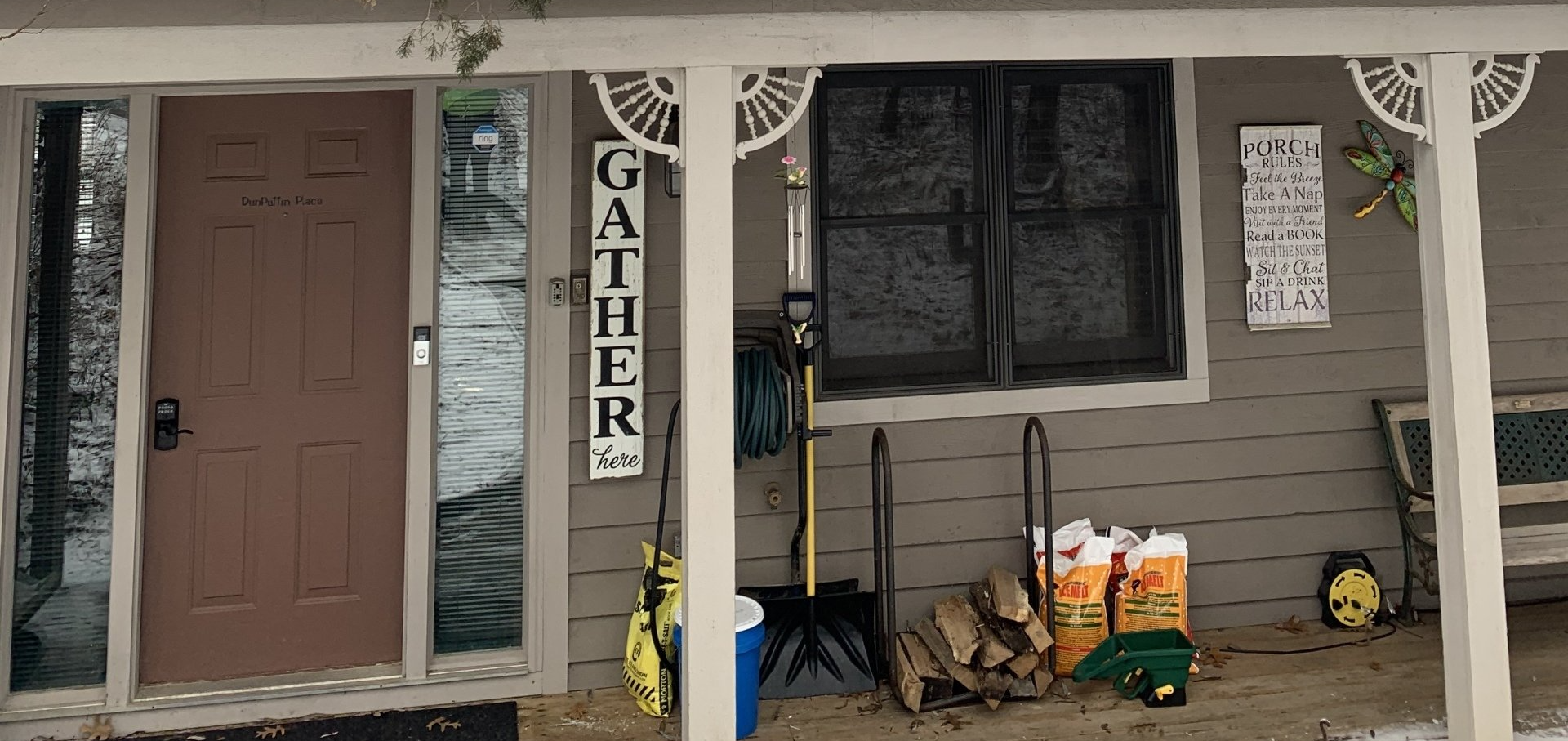 Front porch of a house with a brown door, window, and