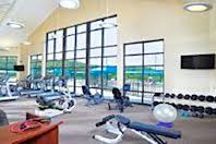 Gym with exercise equipment and large windows.