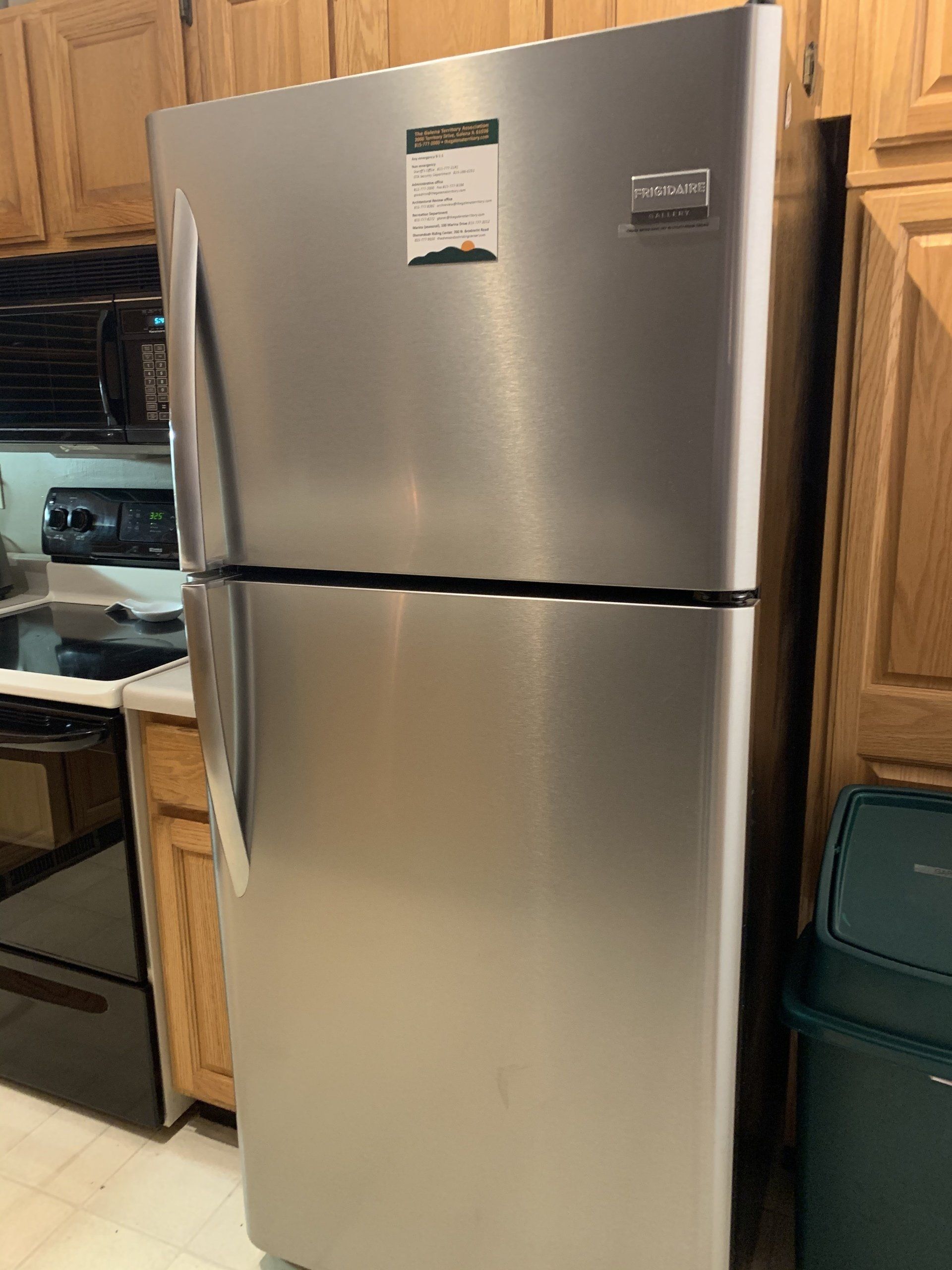 Stainless steel Frigidaire refrigerator in a kitchen with wooden cabinets.