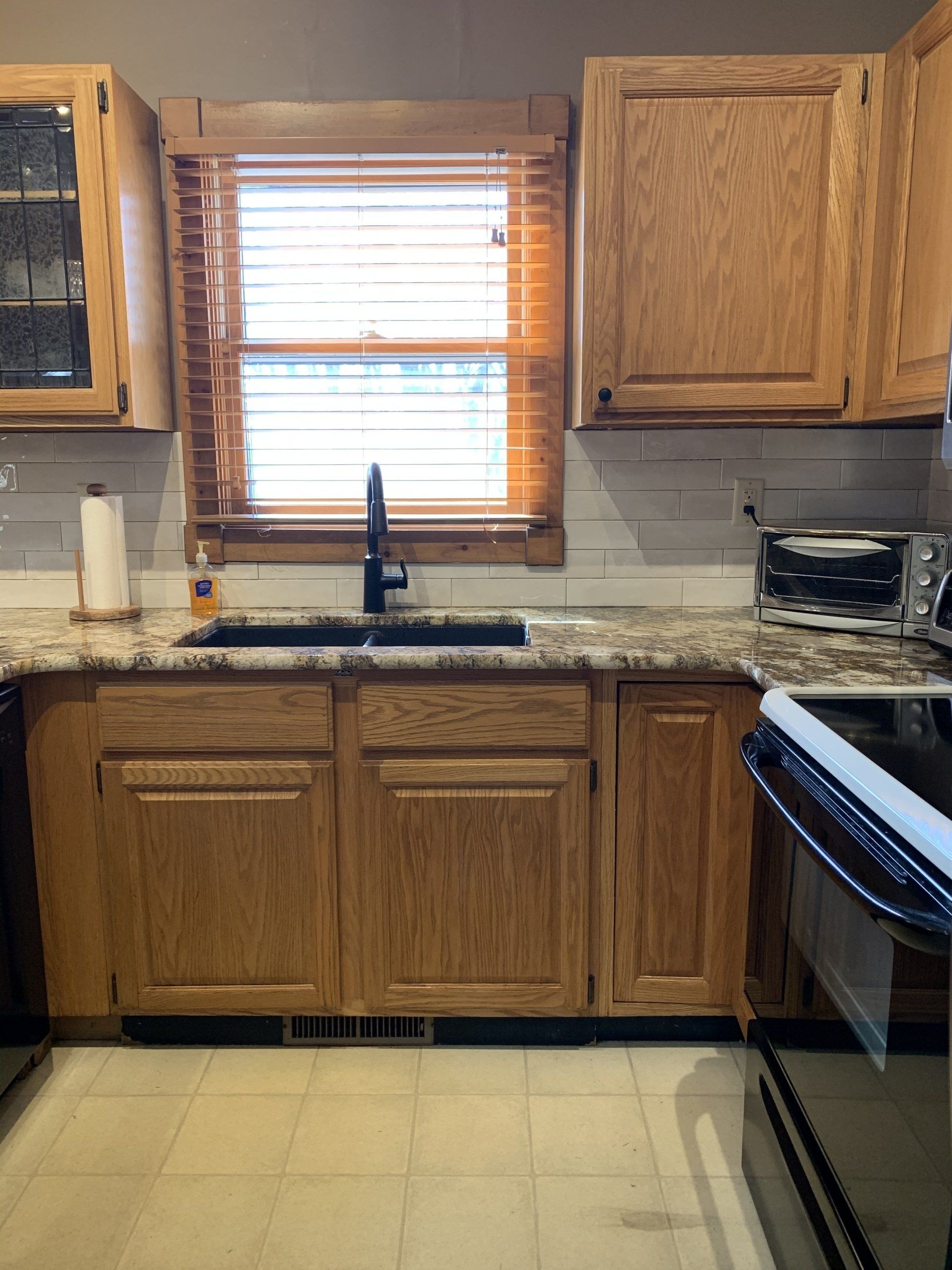 Kitchen cabinets and countertop with a window, sink, and appliances.
