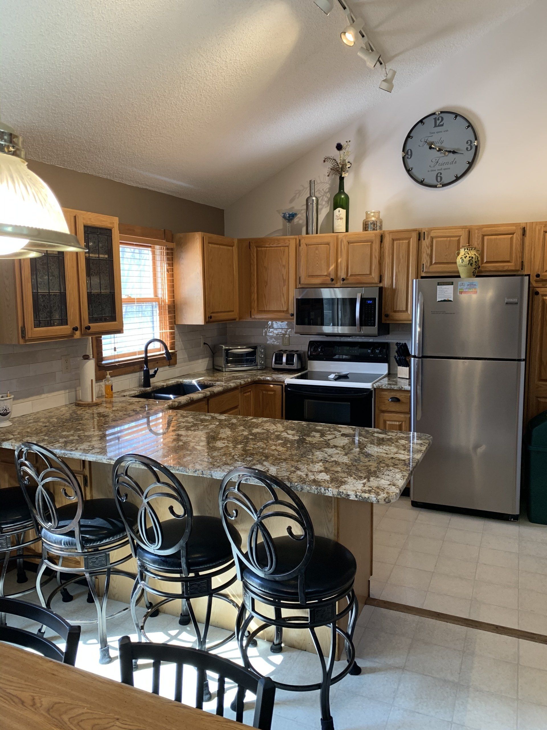 Kitchen with granite countertops, stainless steel appliances, and bar seating.