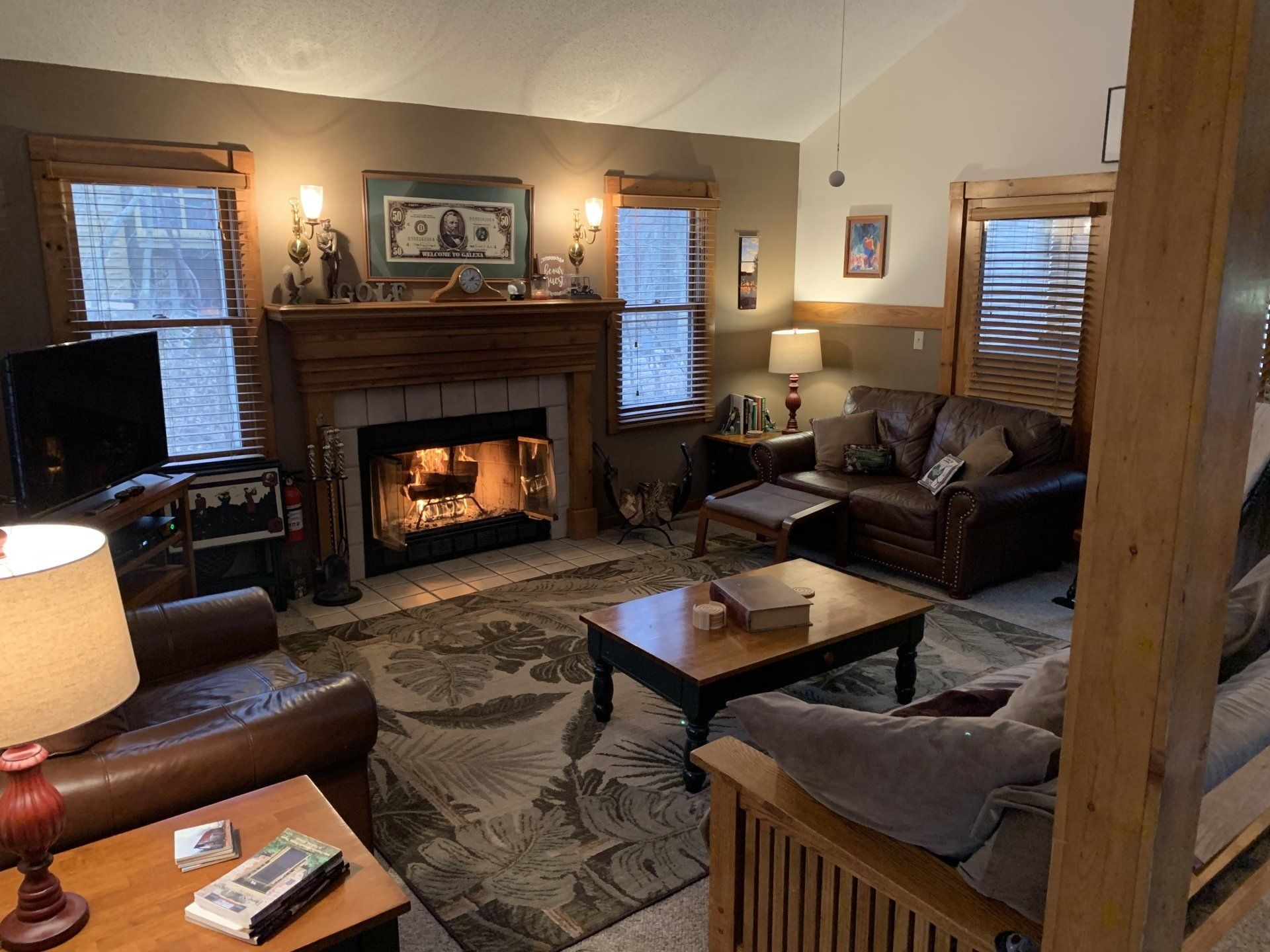Cozy living room with fireplace, leather furniture, wooden accents, and warm lighting.