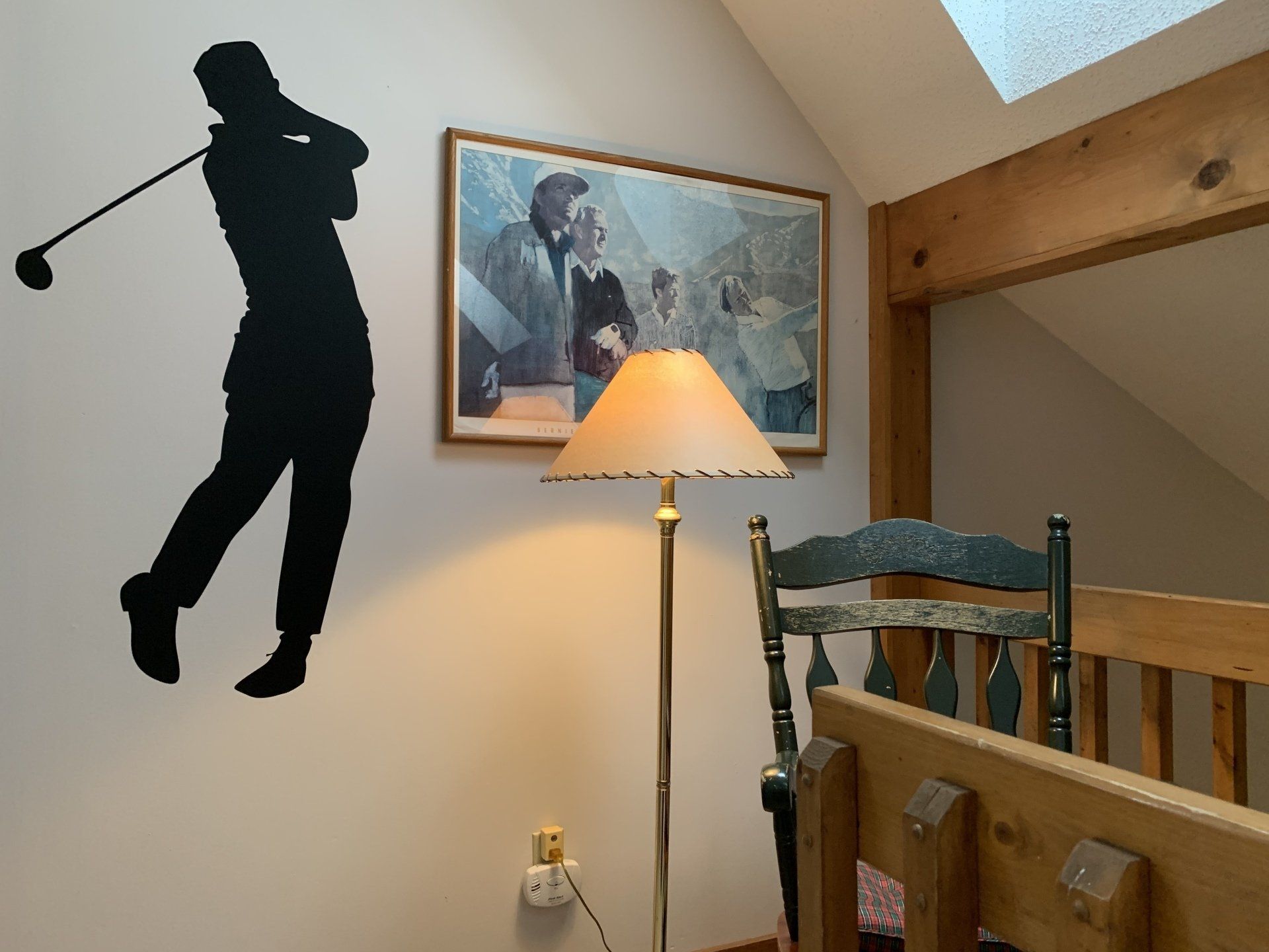 Silhouette of a golfer, painting, lamp, chair, and wooden beams in a room.