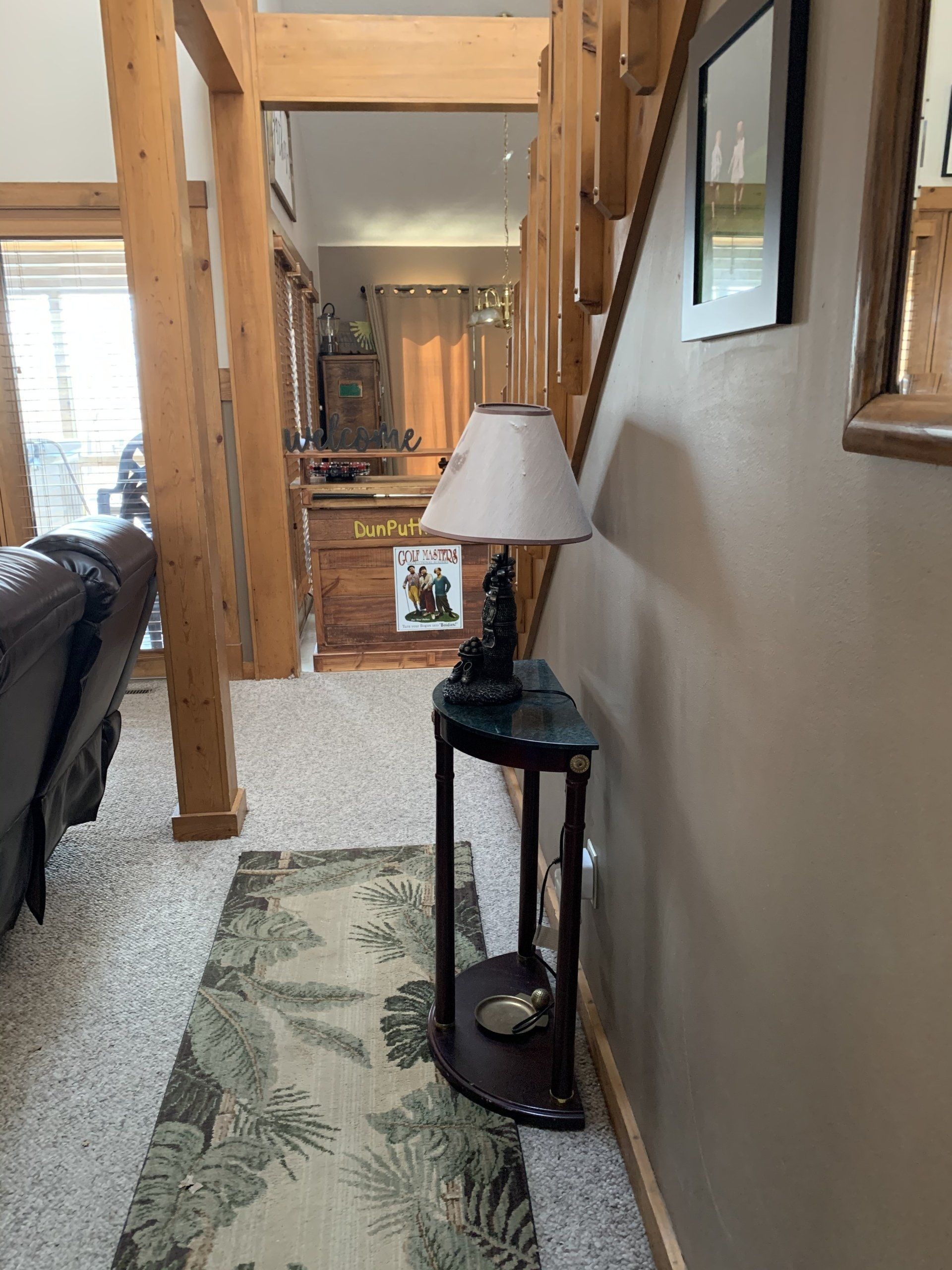 Hallway with a rug, lamp, staircase, and wood beams.