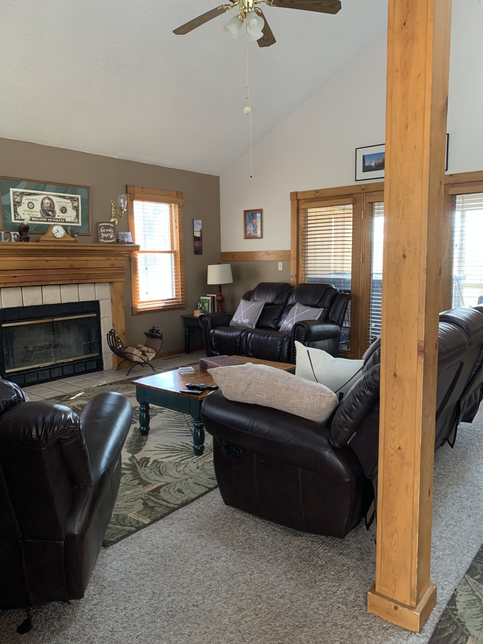 Living room with fireplace, leather furniture, wooden accents, and vaulted ceiling.