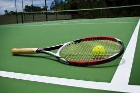 Tennis racket and ball on a green court, near white lines and net.