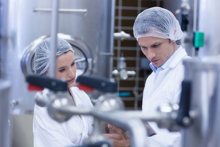 Un hombre y una mujer miran una tableta en una fábrica.