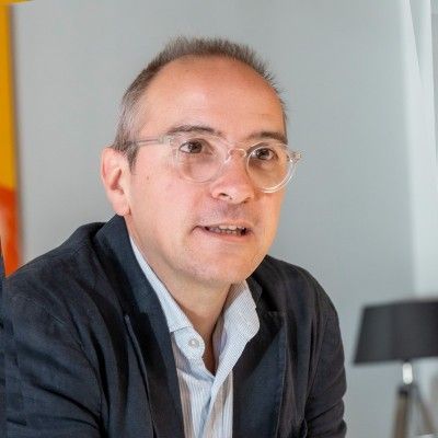 Un hombre que lleva gafas y una chaqueta está sentado en una mesa.