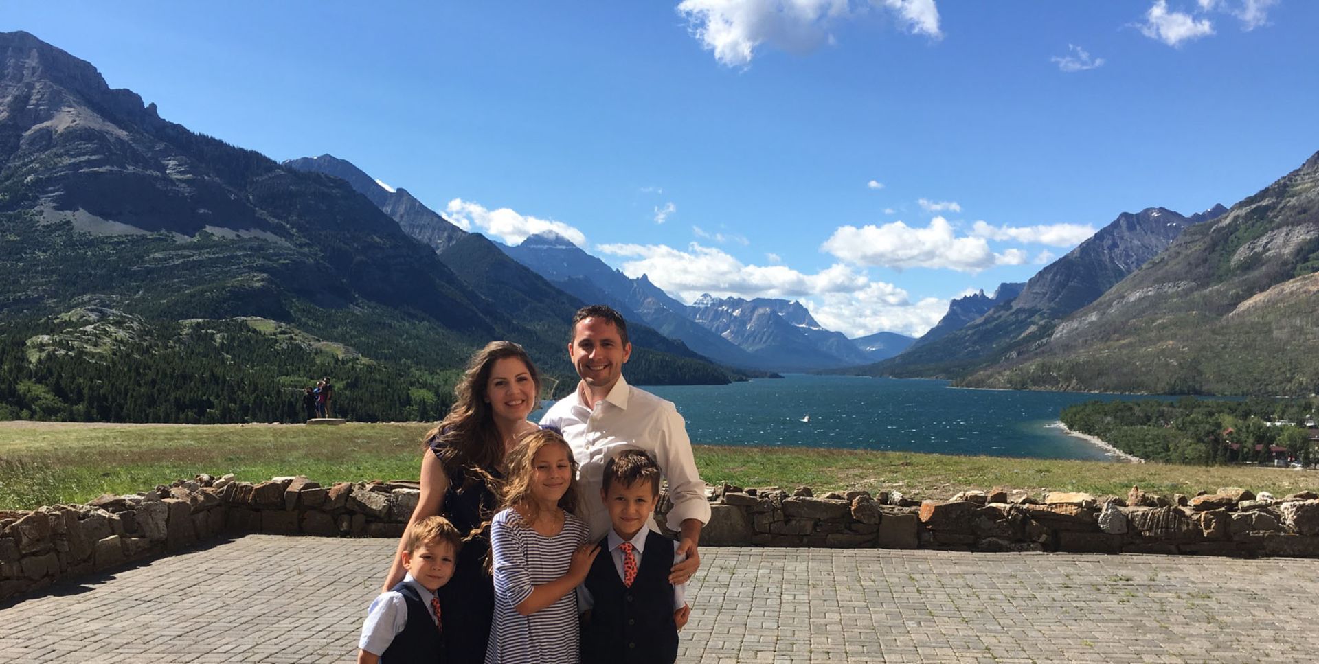 Michael with his family at a lake surrounded by mountains.