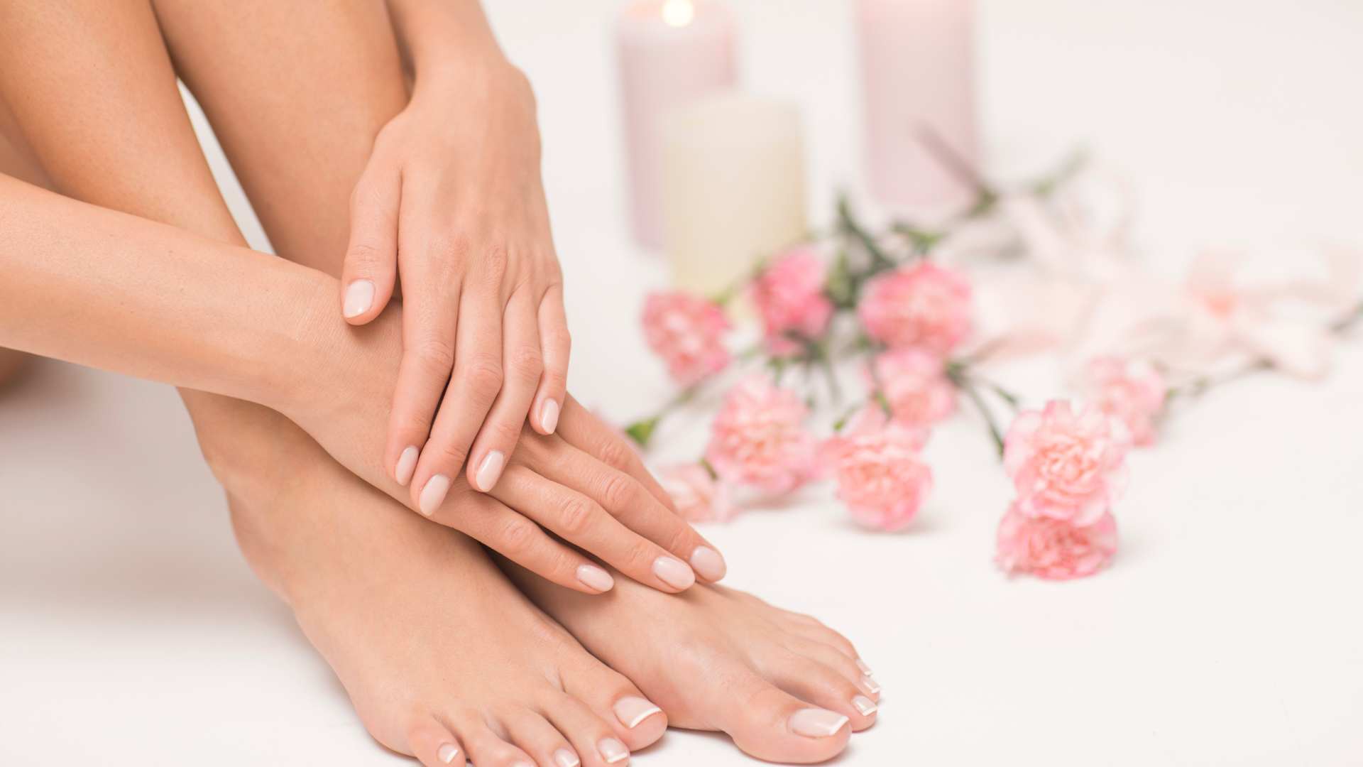 A woman is sitting on the floor with her legs crossed and her hands on her feet.