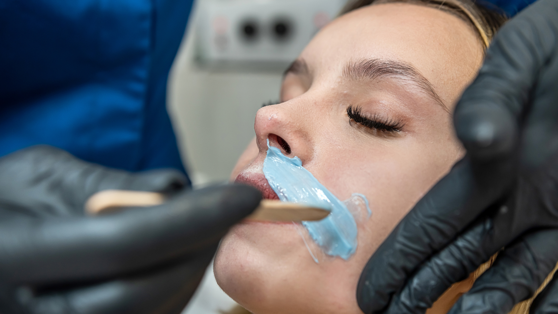 A woman is getting a wax treatment on her face.