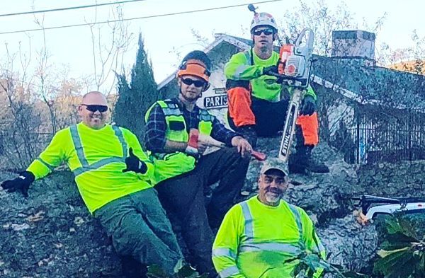 A group of men are sitting on a rock with a chainsaw.