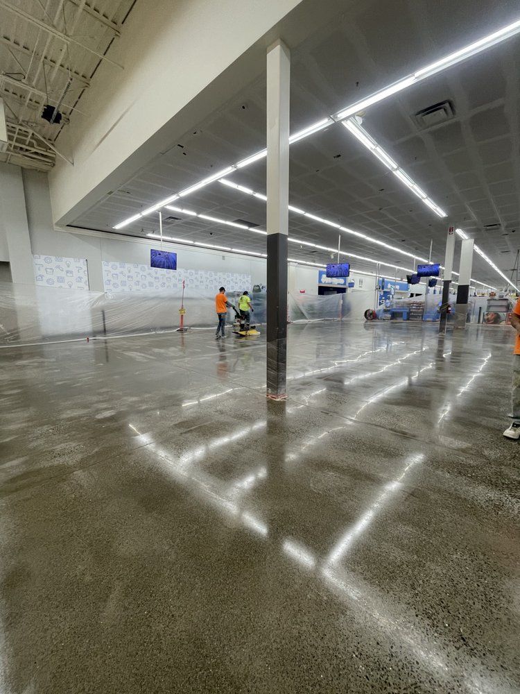 Wet grocery store floor being cleaned by workers under bright fluorescent lights