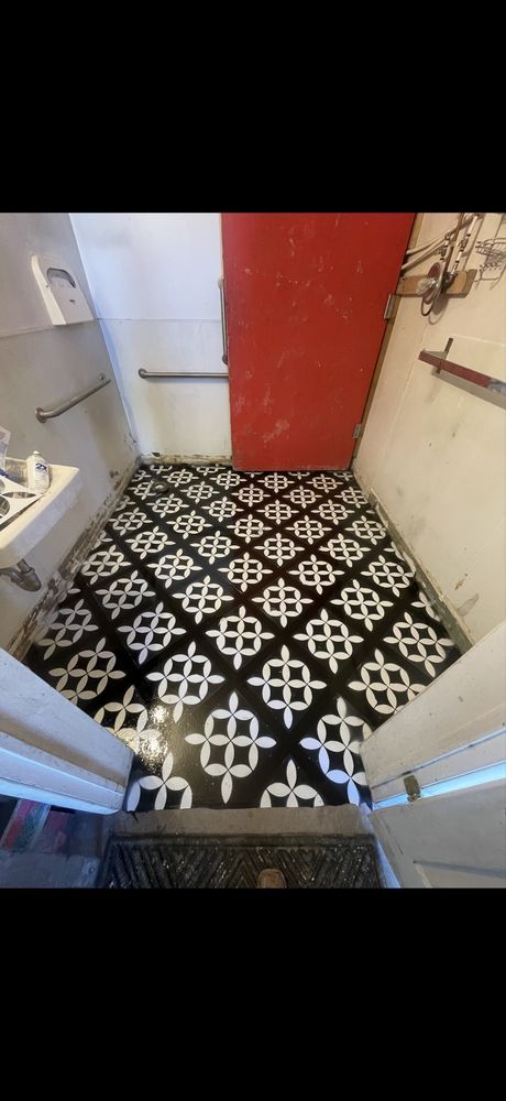 Small tiled bathroom with a red door and black-and-white patterned floor, viewed from the doorway
