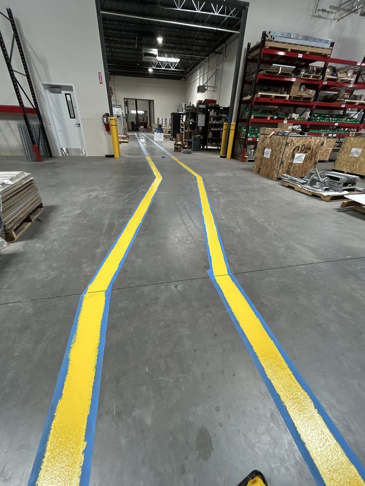 Warehouse aisle with yellow and blue floor markings leading toward shelves and work area