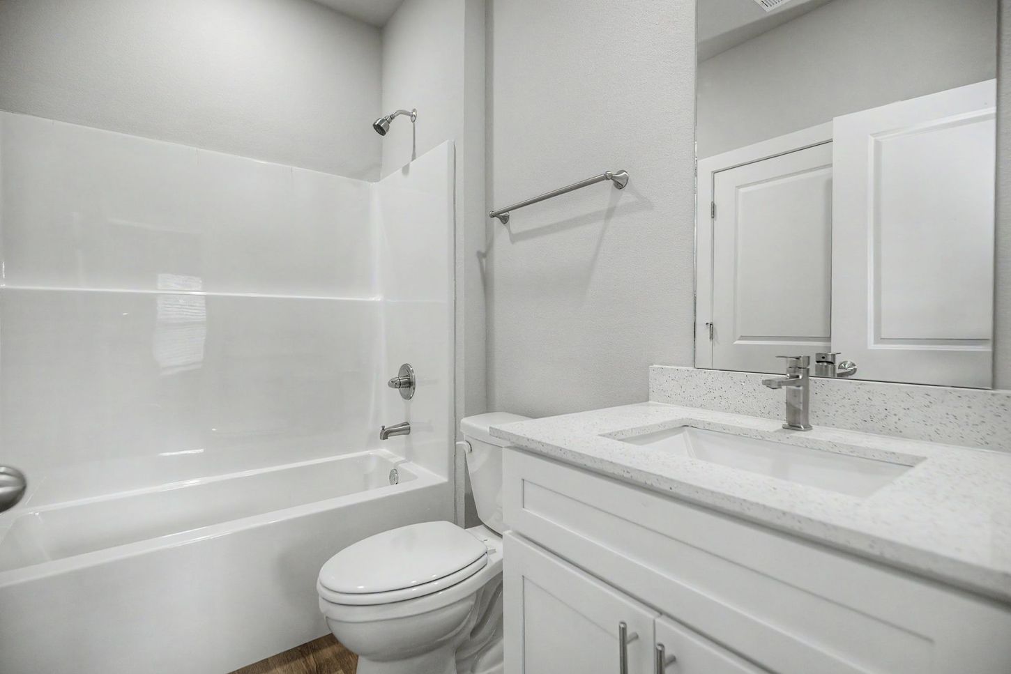Bright white bathroom with tub, toilet, and vanity sink nearby
